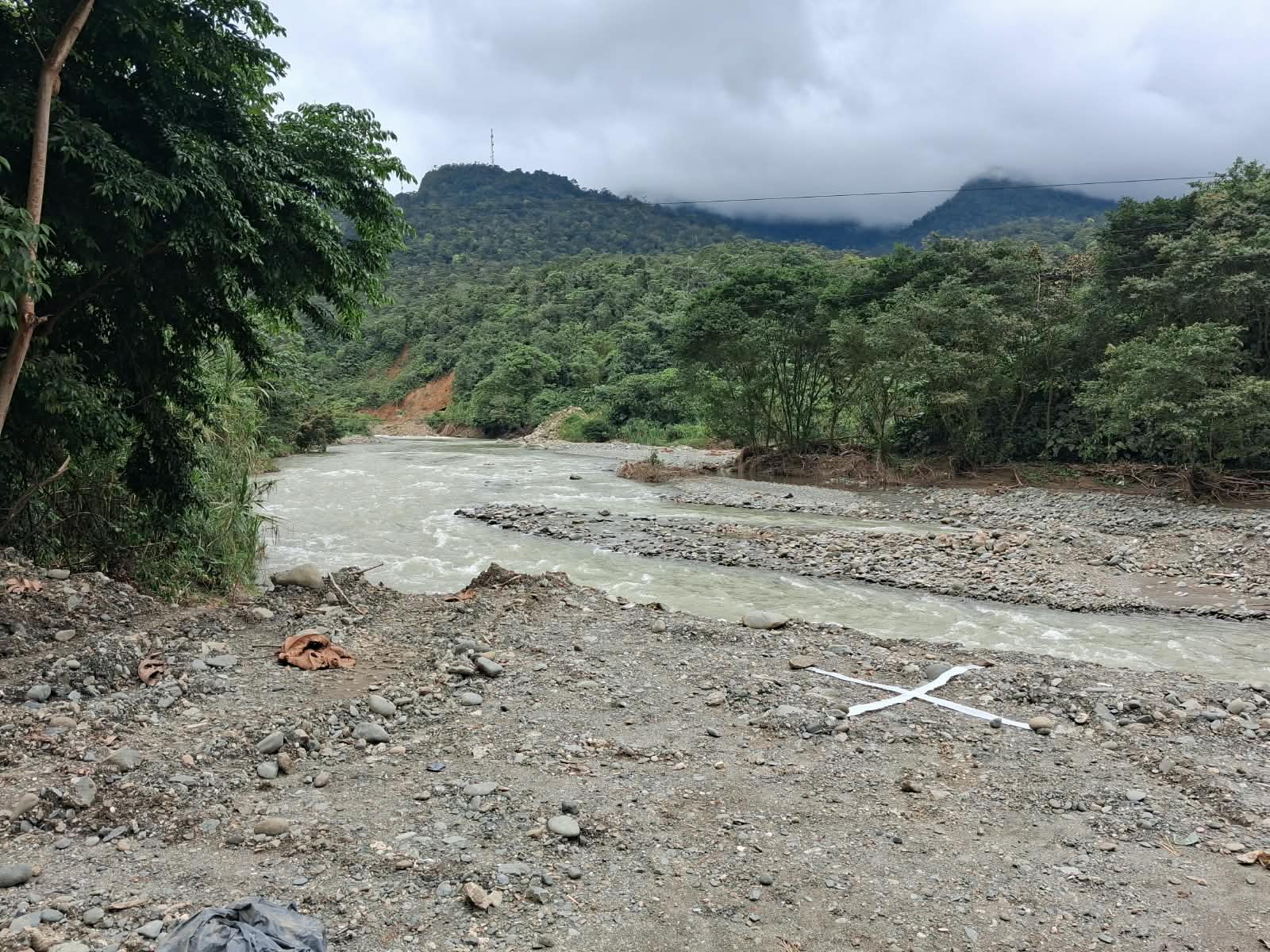 El río Dagua a su paso por Zaragoza, con orillas de piedra y montañas cubiertas de selva bajo un cielo nublado